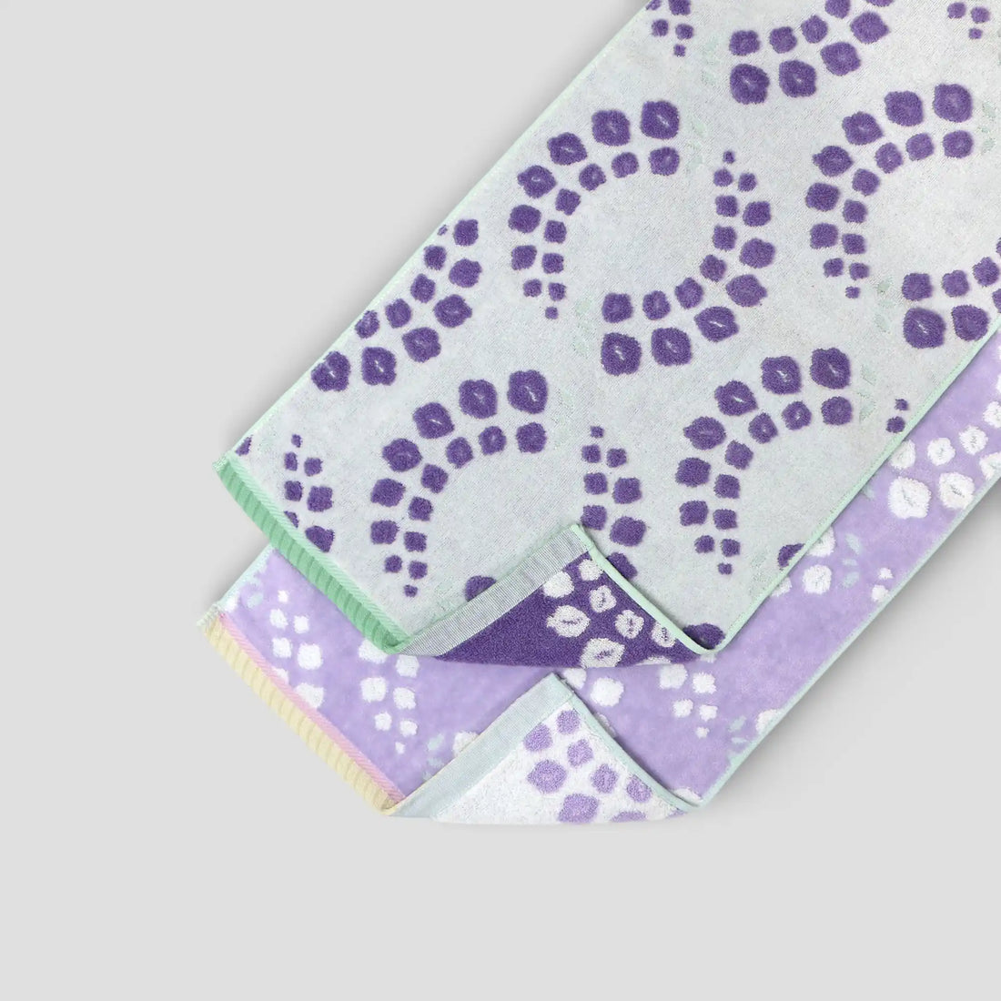 Set of two fabric swatches Imabatri towel with purple floral patterns on a light gray background