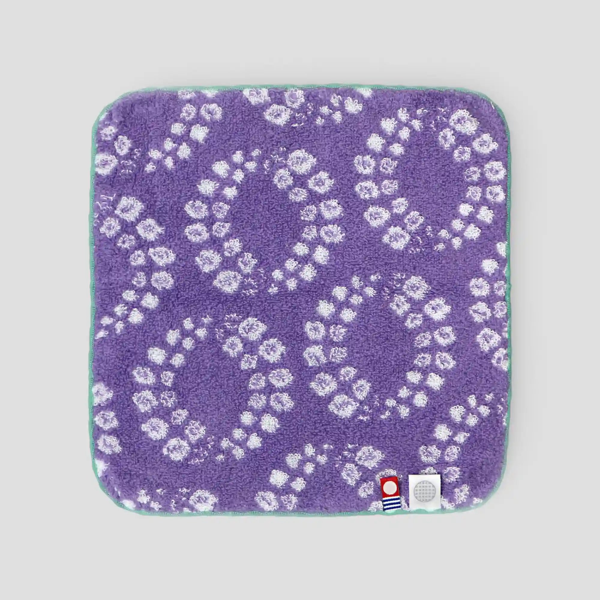 Purple Imabari towel back-side with white floral pattern on a gray background