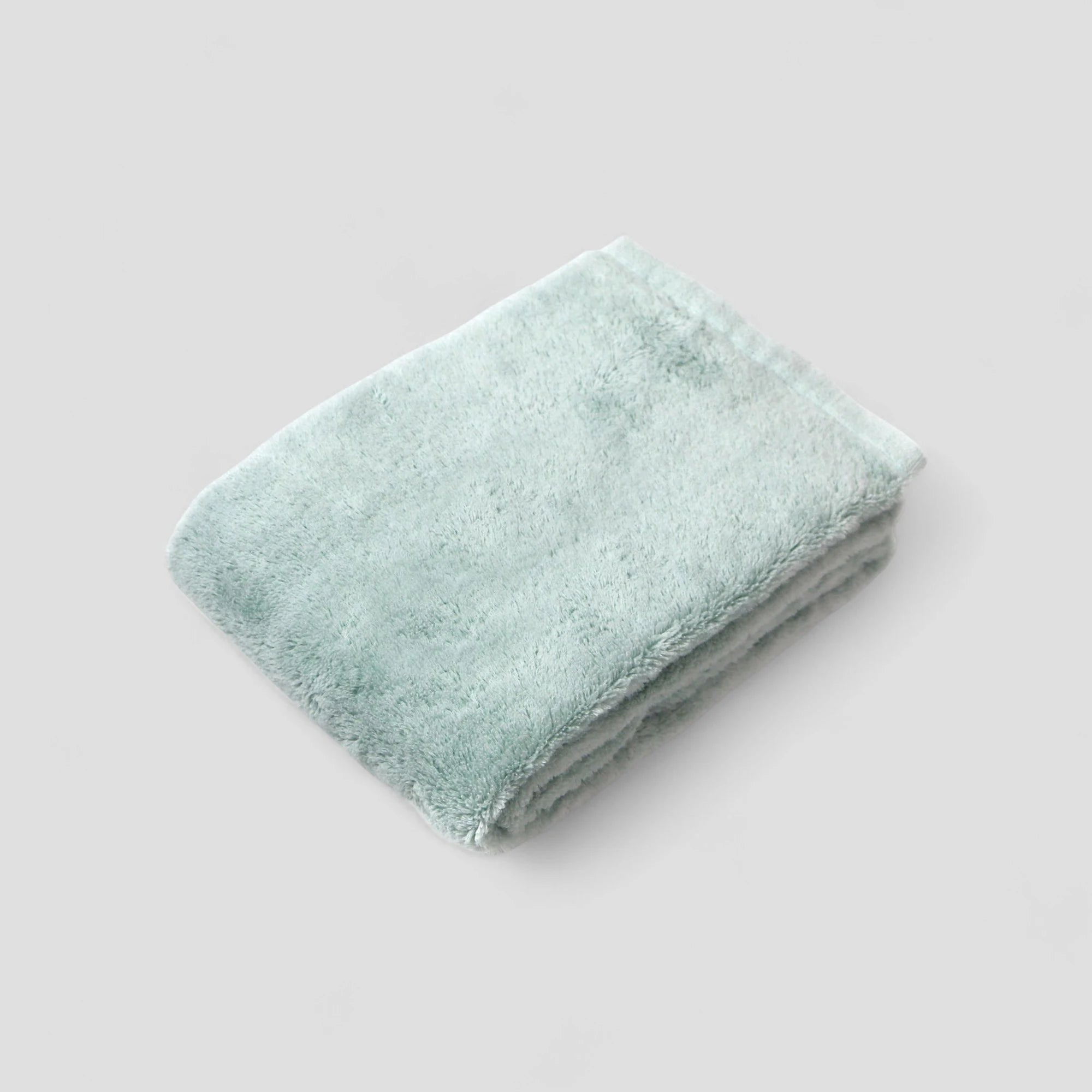 Folded light blue Imabari towel on a white background