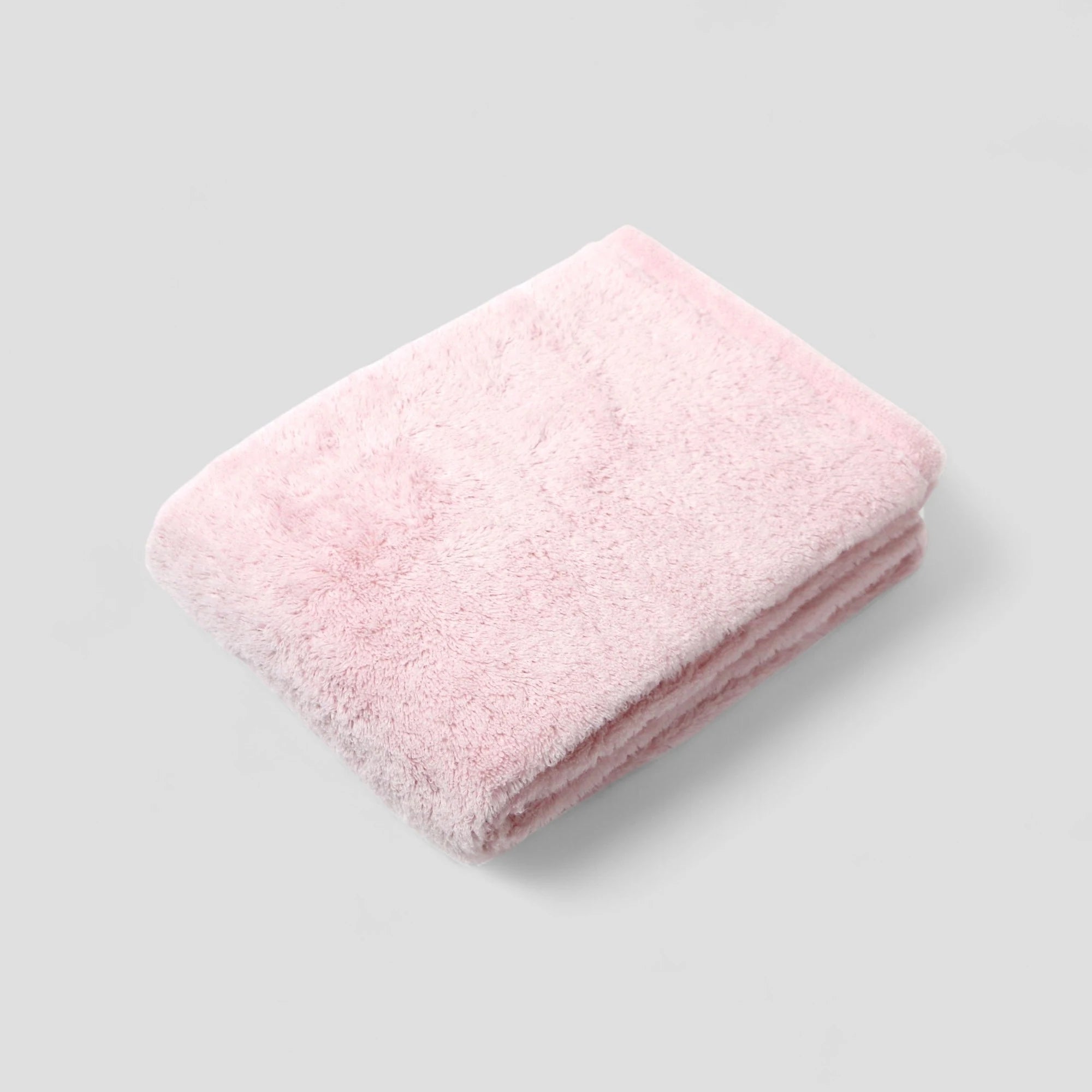 Folded pink Imabari towel on a light gray background