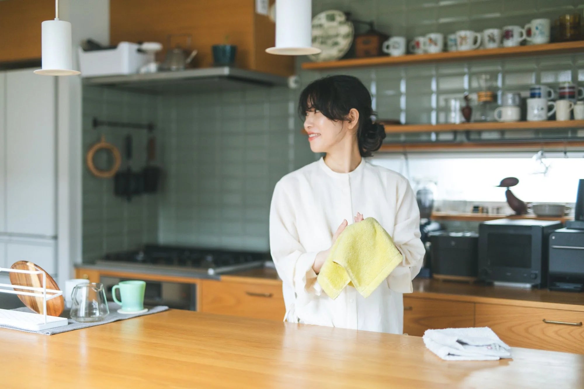Woman in a kitchen holding a yellow Imabari towel