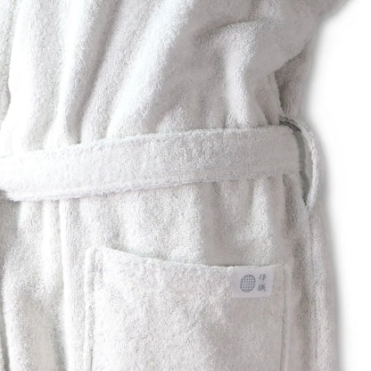 Close-up of a white terry cloth Imabari towel bathrobe with a matching belt and a front pocket, shown against a plain white background.