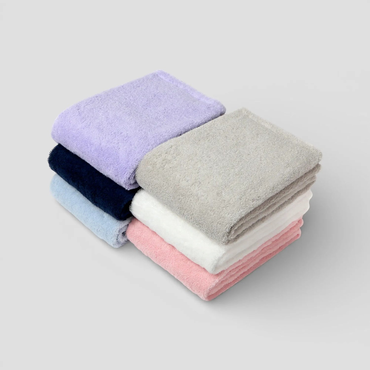 Stack of folded Imabari towels in various colors on a light gray background