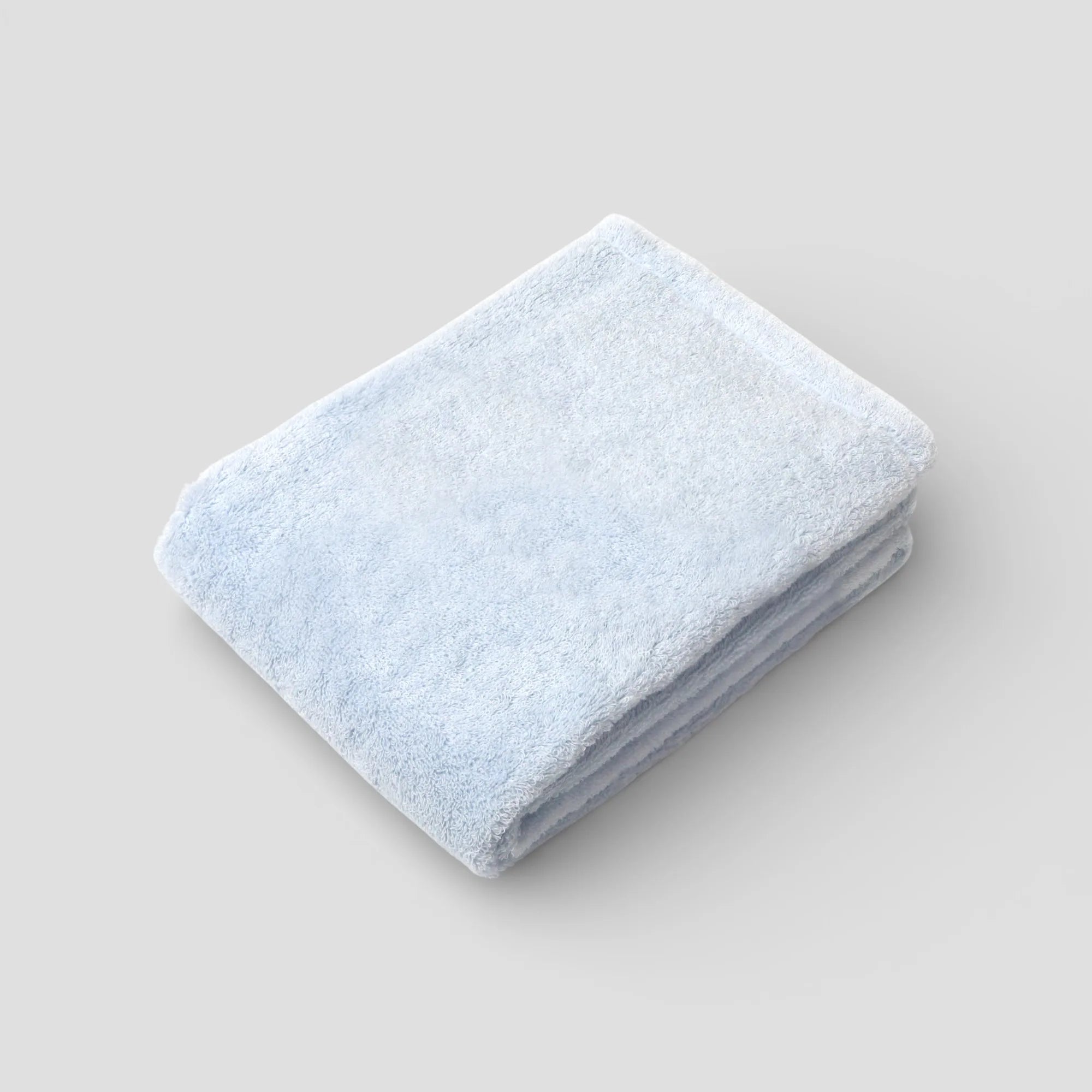 Folded light blue Imabari towel on a gray background