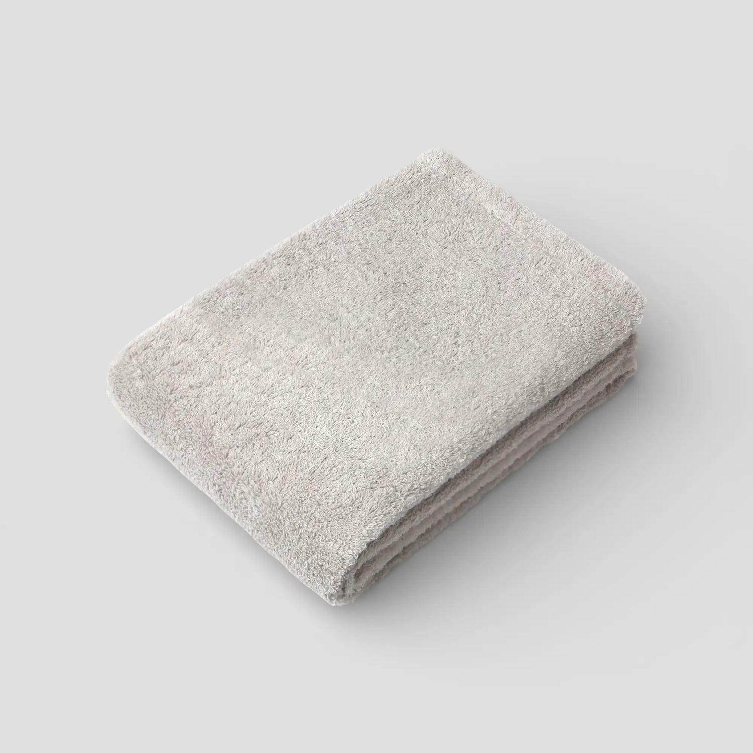 Folded beige Imabari towel on a light gray background