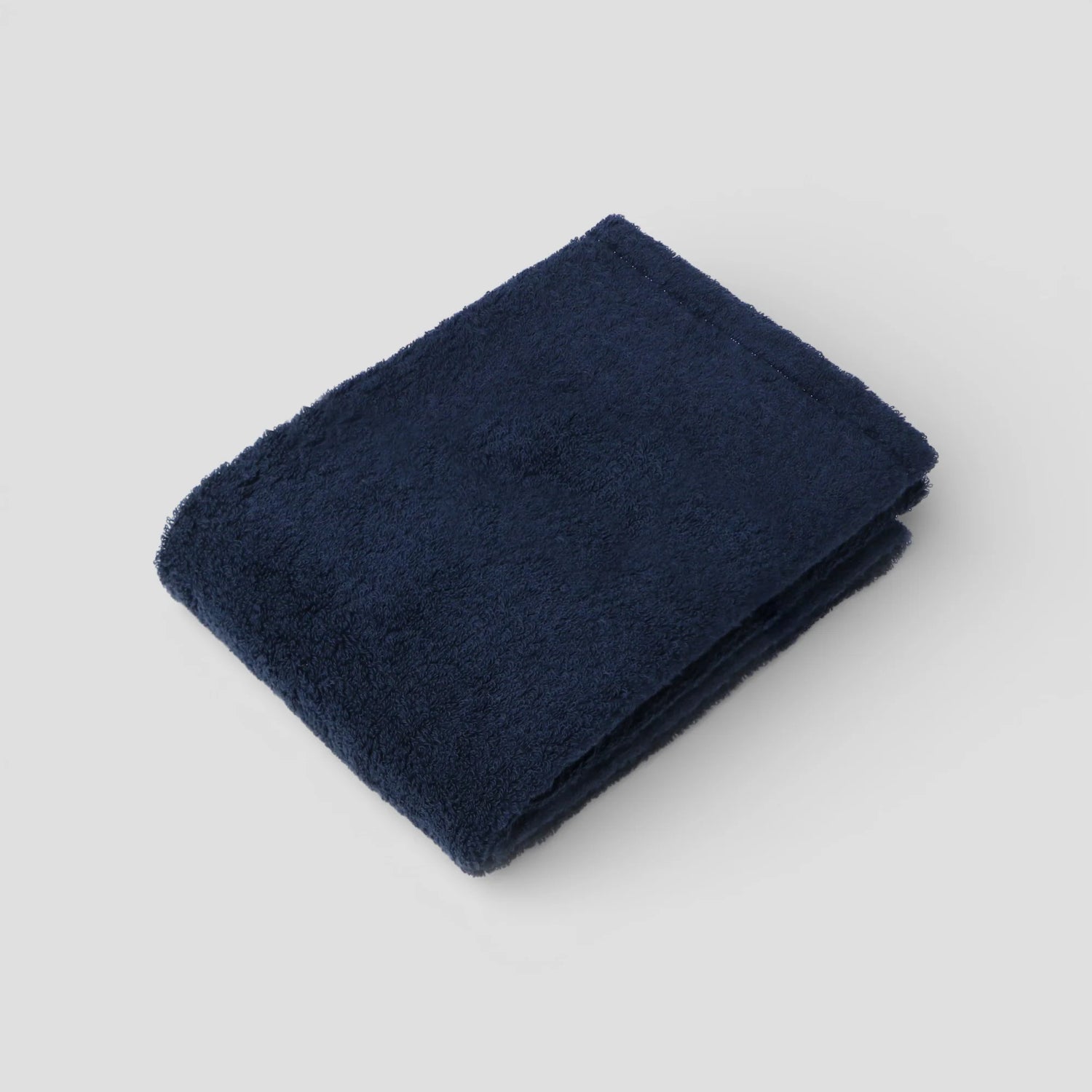 Folded navy blue Imabari towel on a light gray background