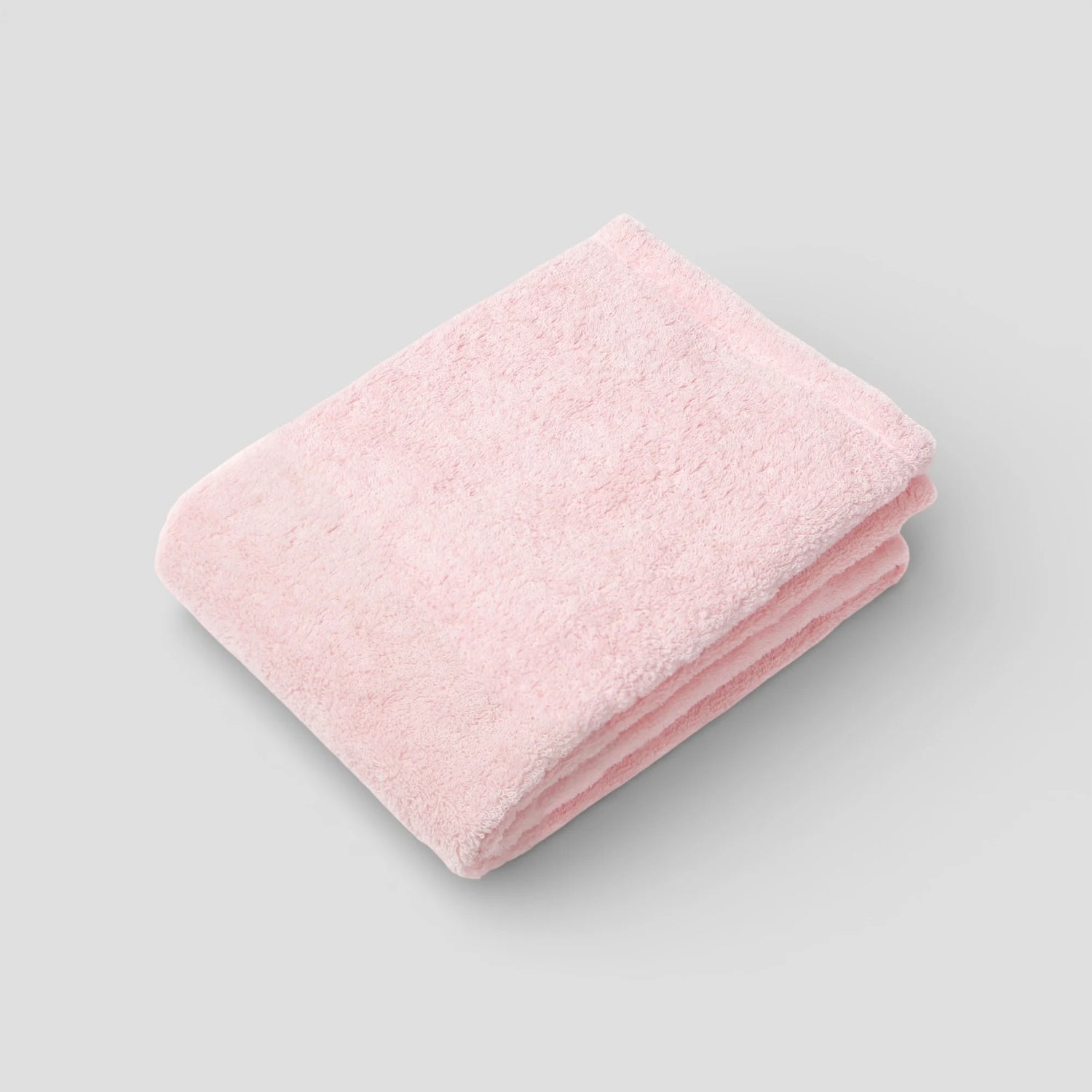 Folded pink Imabari towel on a light gray background