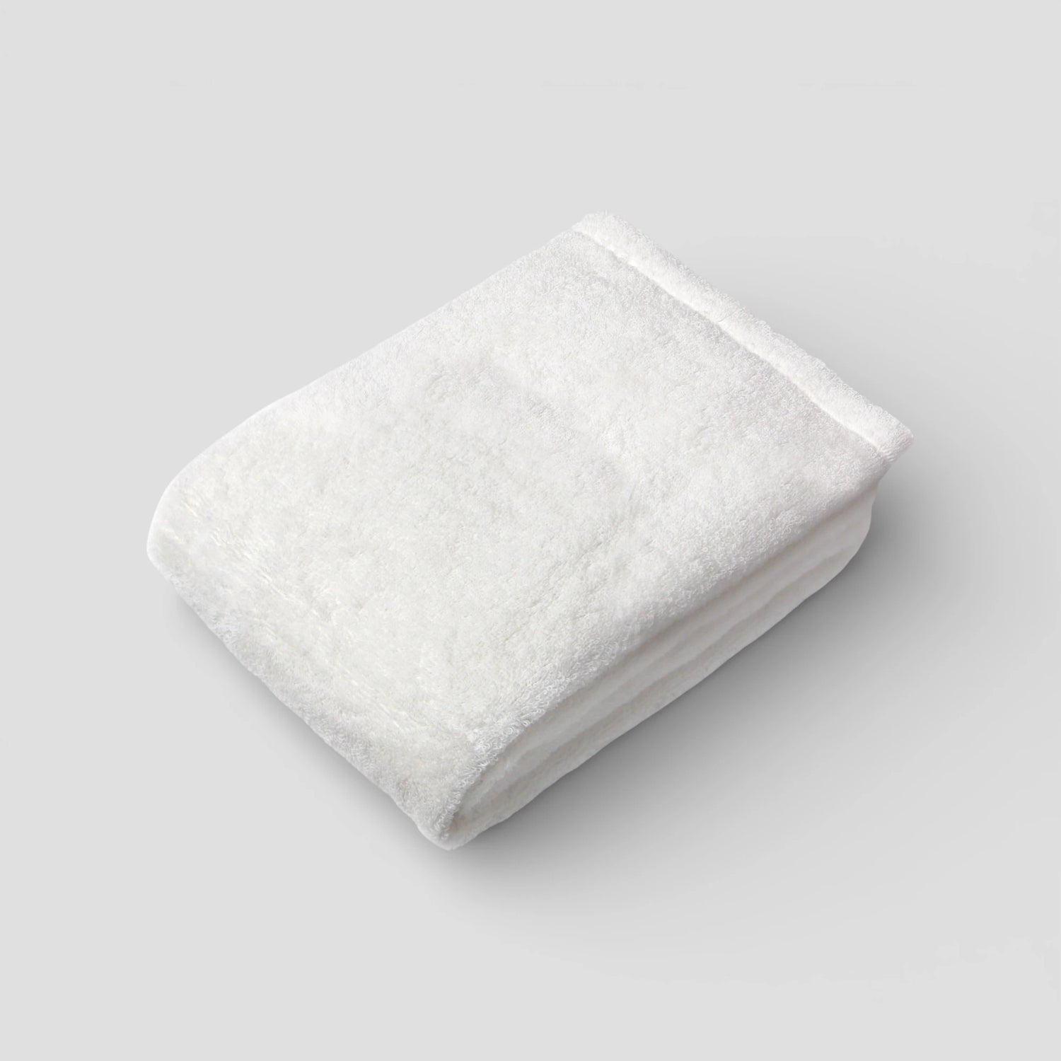 Folded white Imabari towel on a light gray background