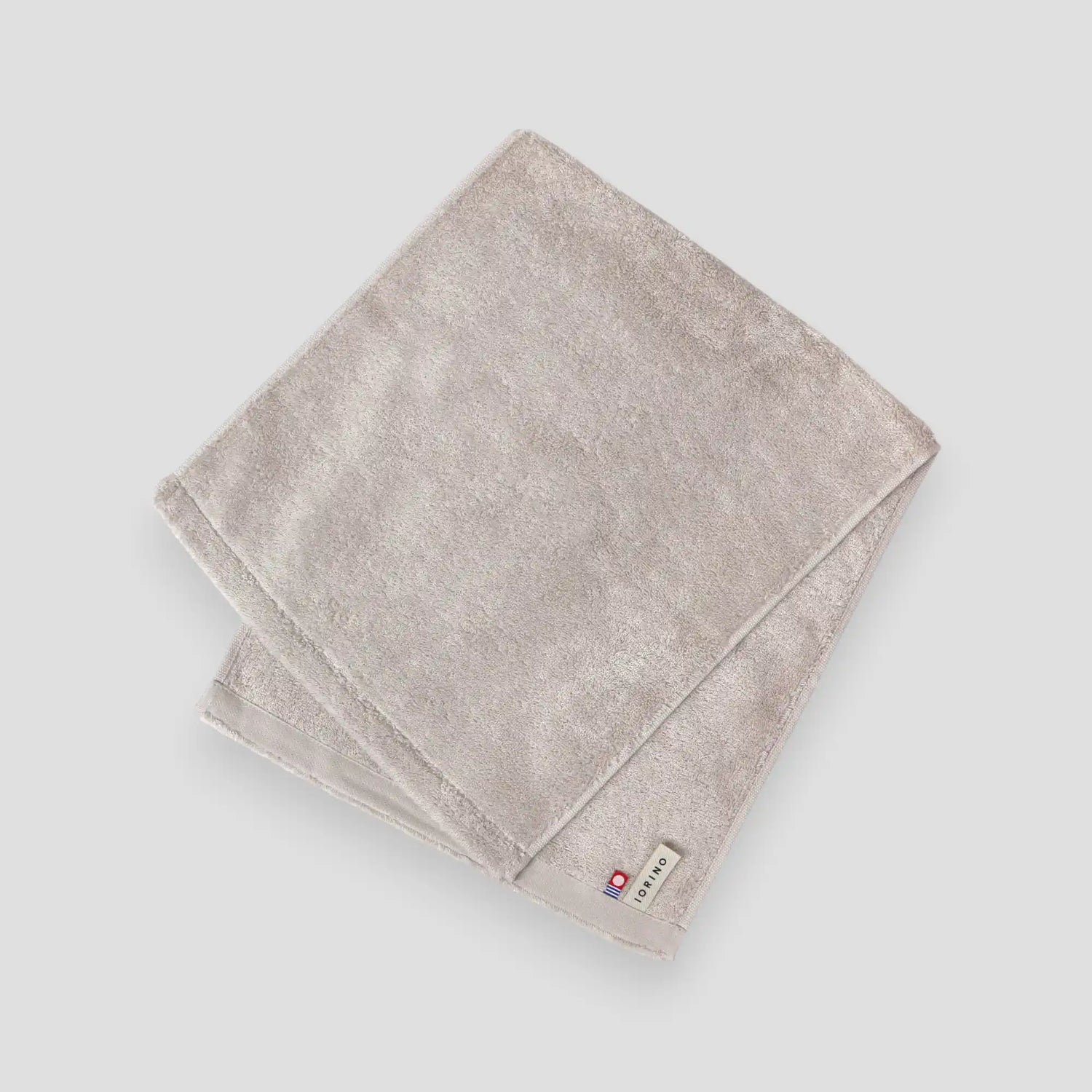 Folded beige Imabari towel on a light gray background
