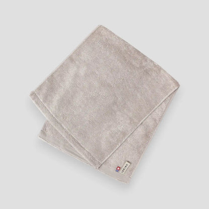 Folded beige Imabari towel on a light gray background