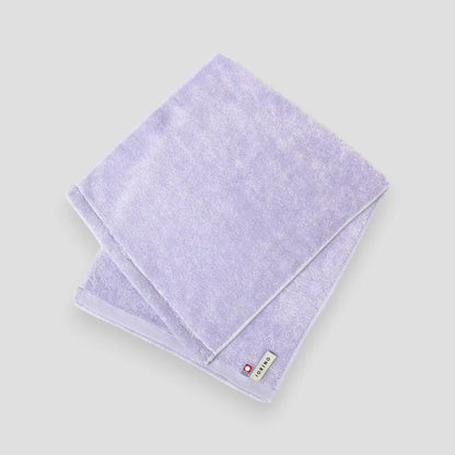 Folded light purple Imabari towel on a white background