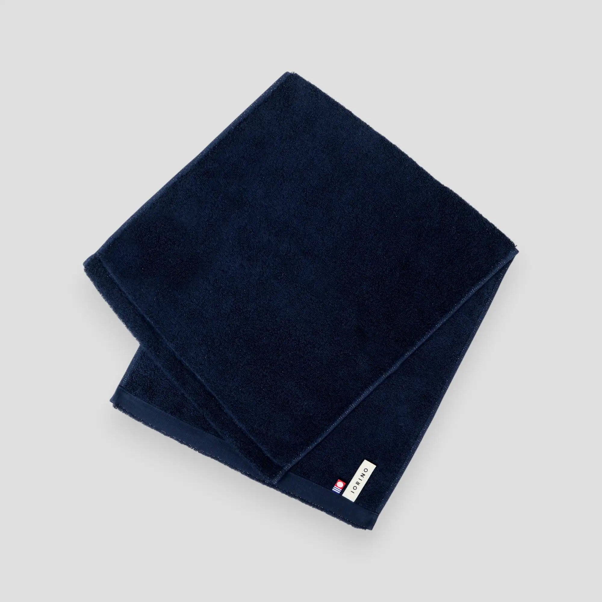 Folded navy blue Imabari towel on a light gray background