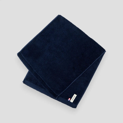 Folded navy blue Imabari towel on a light gray background