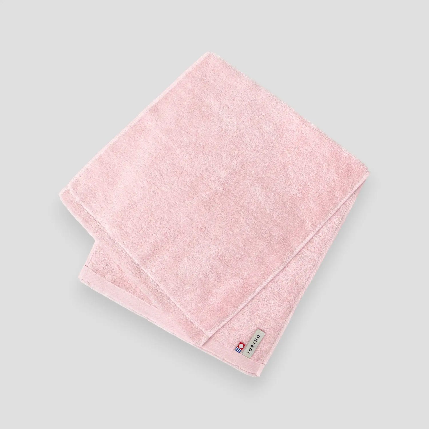 Pink Imabari towel with a brand label on a light gray background