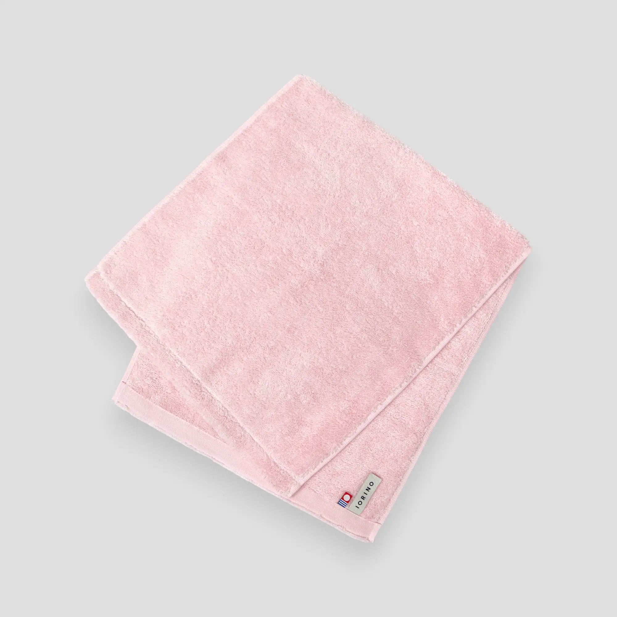 Pink Imabari towel with a brand label on a light gray background