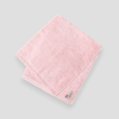 Pink Imabari towel with a brand label on a light gray background