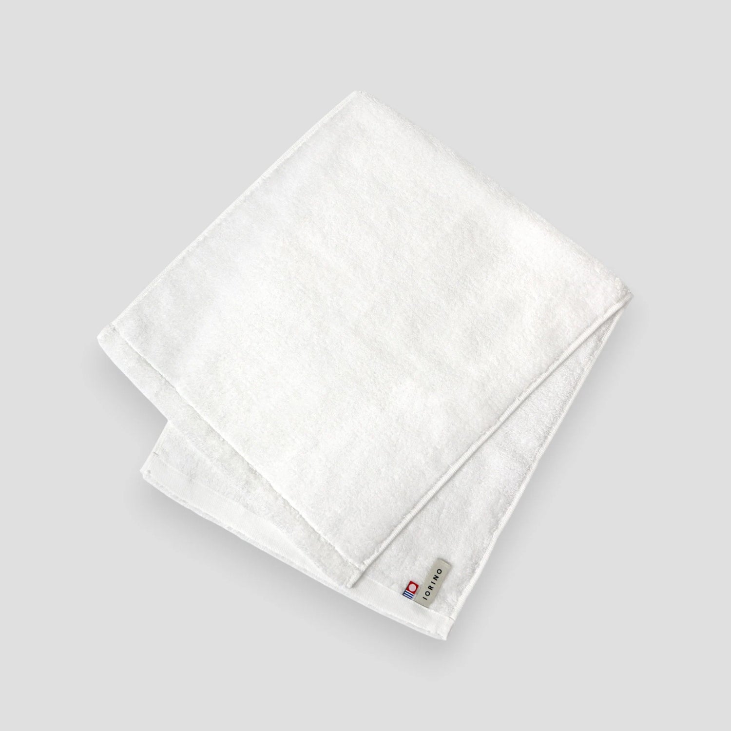 Folded white Imabari towel on a light gray background