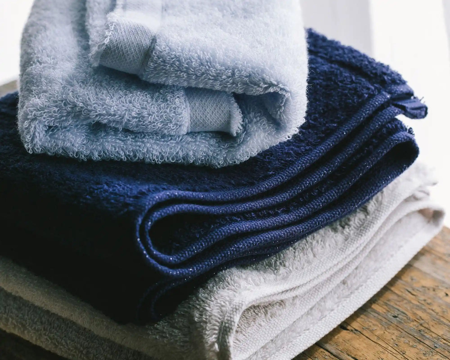 Stack of folded Imabari towels in various colors on a wooden surface