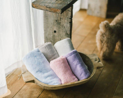 Set of colorful Imabari towels in a wooden basket on a wooden floor.