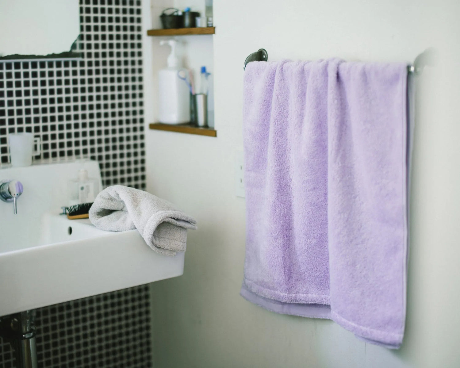 Bathroom with a sink, mirror, and a purple Imabari towel hanging on a rack.