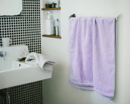 Bathroom with a sink, mirror, and a purple Imabari towel hanging on a rack.
