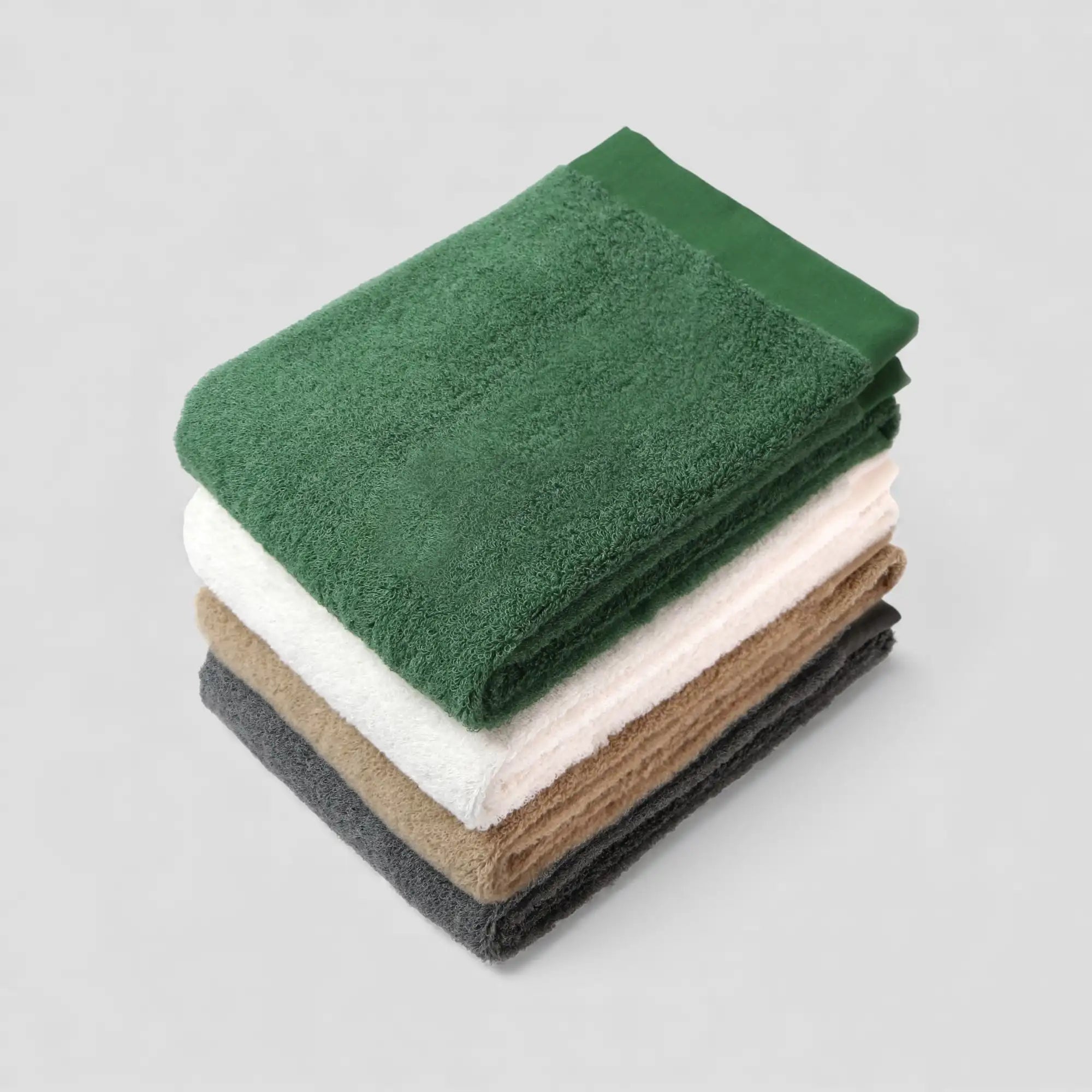 Stack of folded Imabari towels in various colors on a light gray background