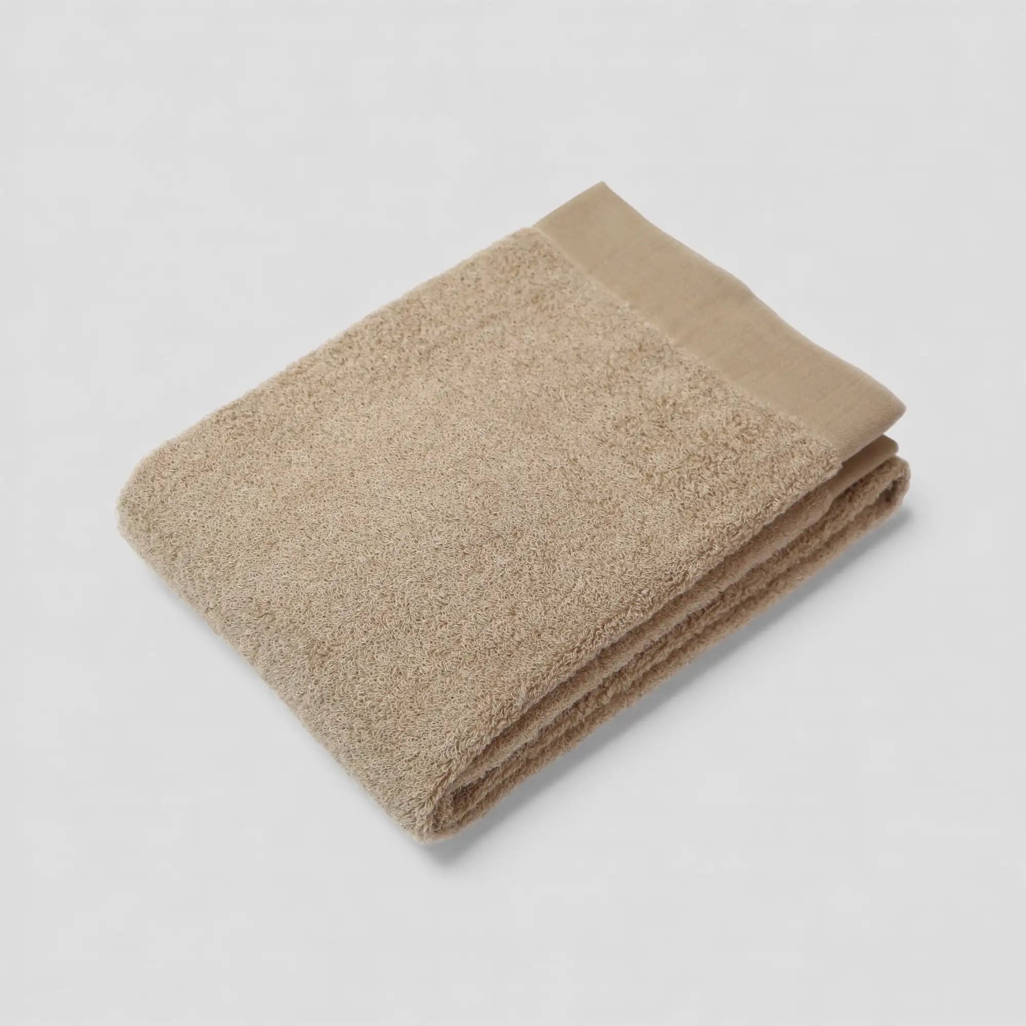 Folded beige Imabari towel on a light gray background