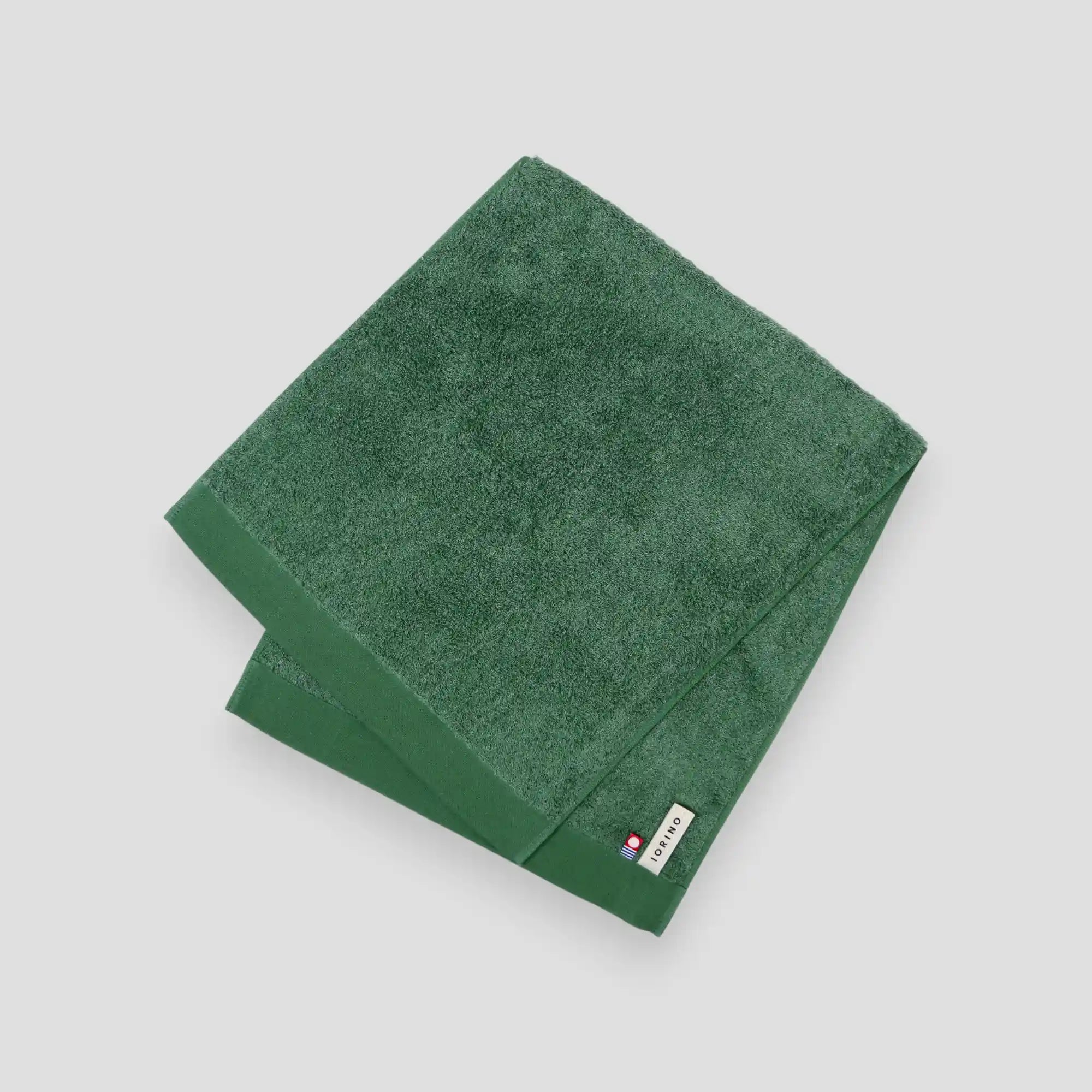 Green Imabari towel with a brand label on a light gray background