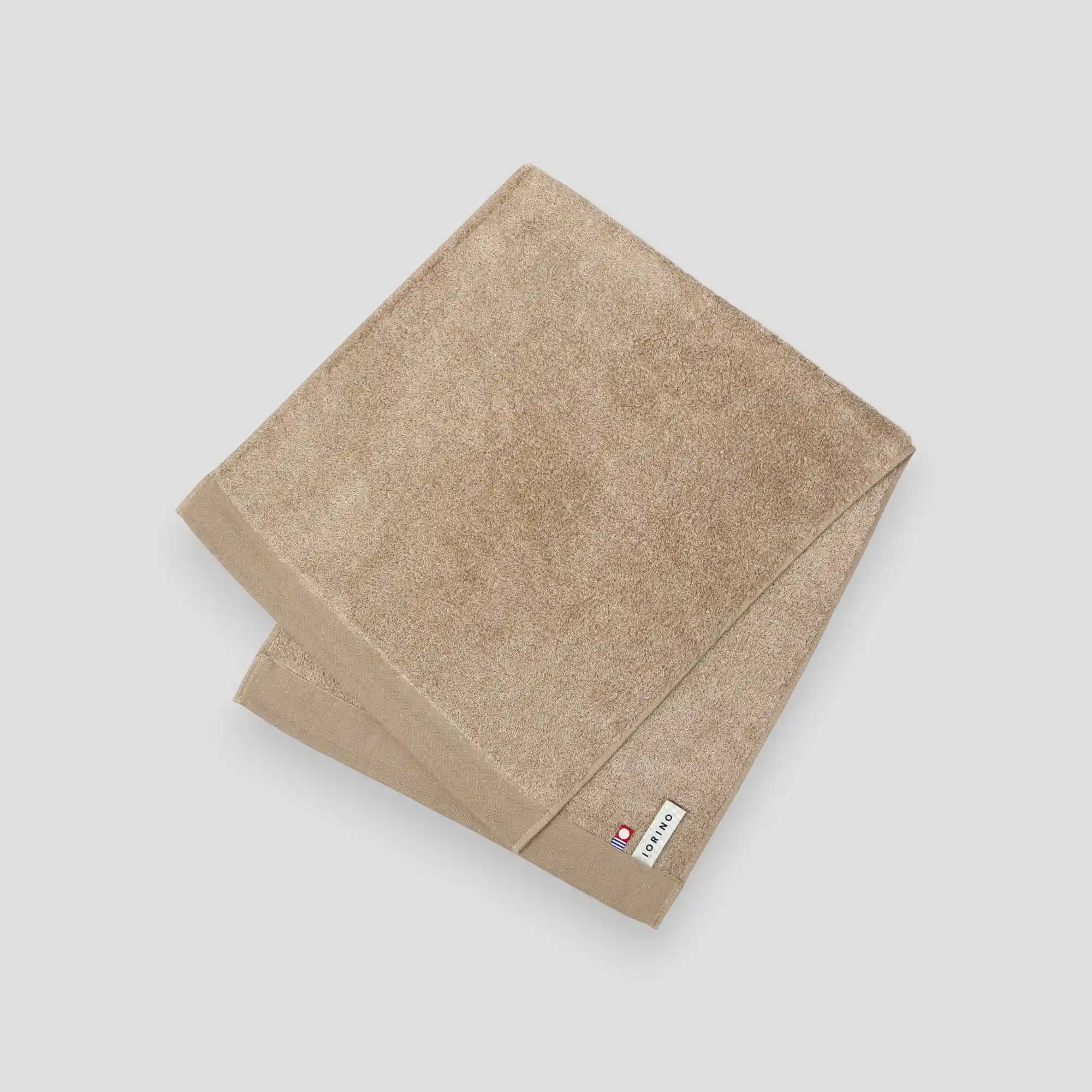 Beige Imabari towel with a brand label on a light gray background
