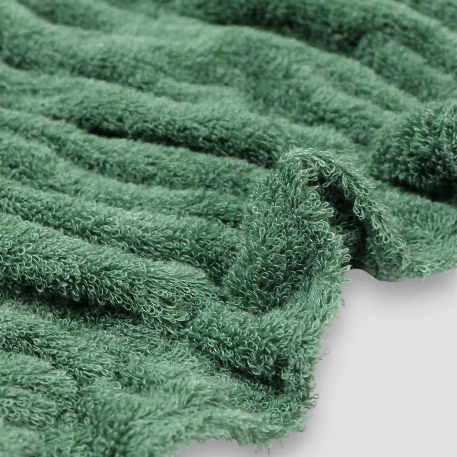 Close-up of a green textured Imabari towel fabric on a white background.