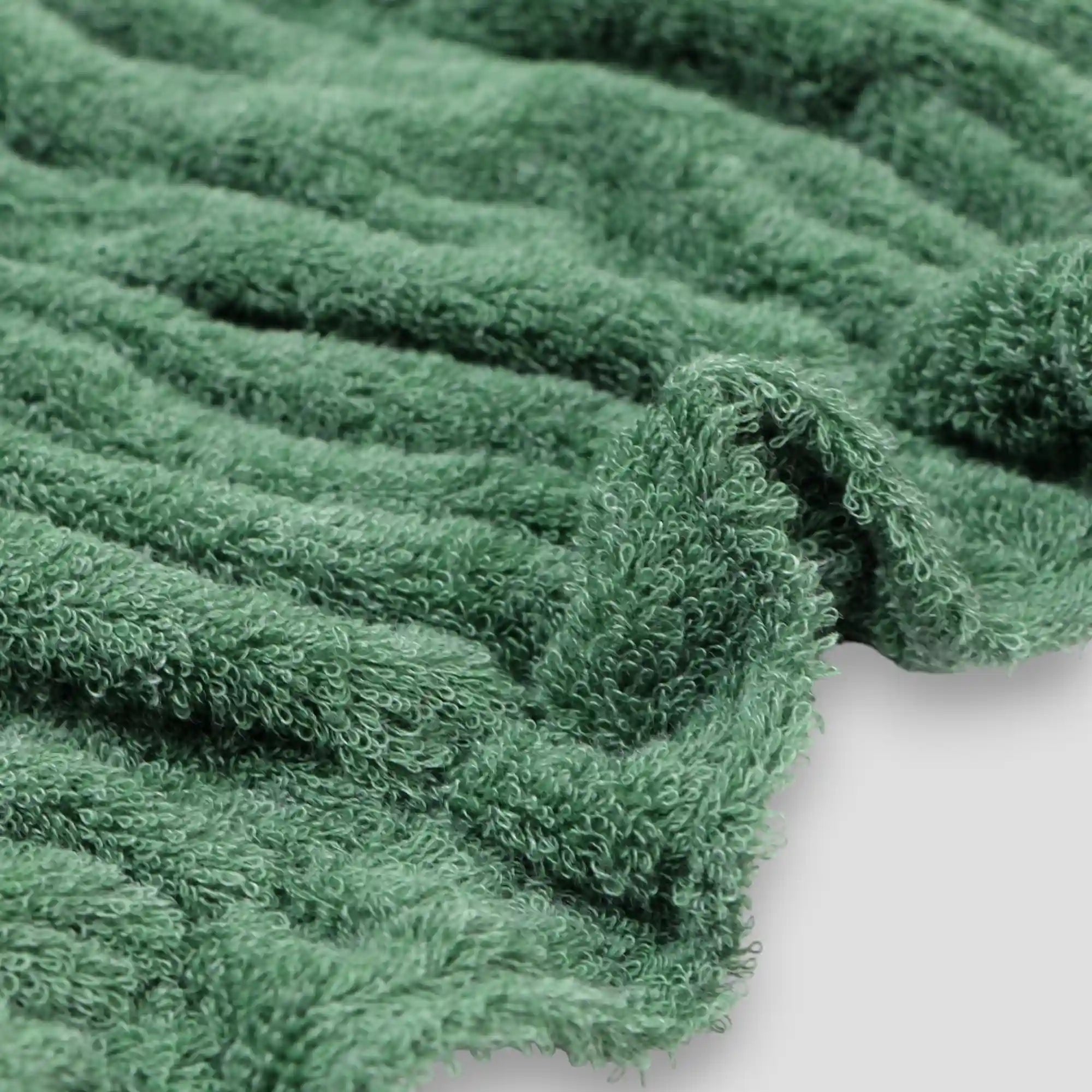 Close-up of a green textured Imabari towel fabric on a white background.