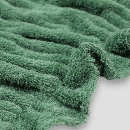 Close-up of a green textured Imabari towel fabric on a white background.