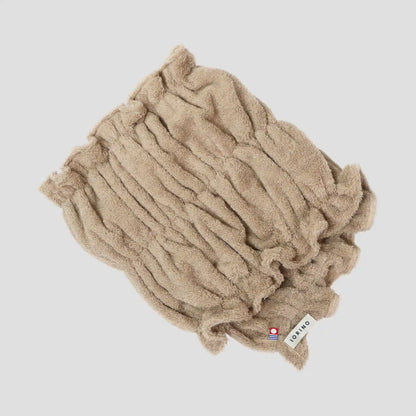 Beige Imabari towel with a brand label on a light gray background