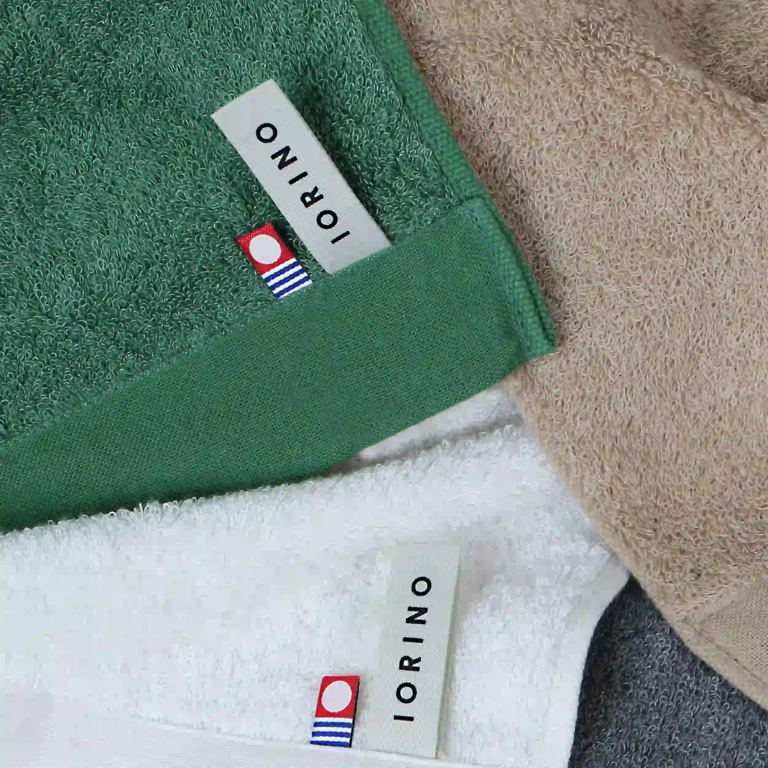 Close-up of green, white, and beige Imabari towels with IORINO labels.