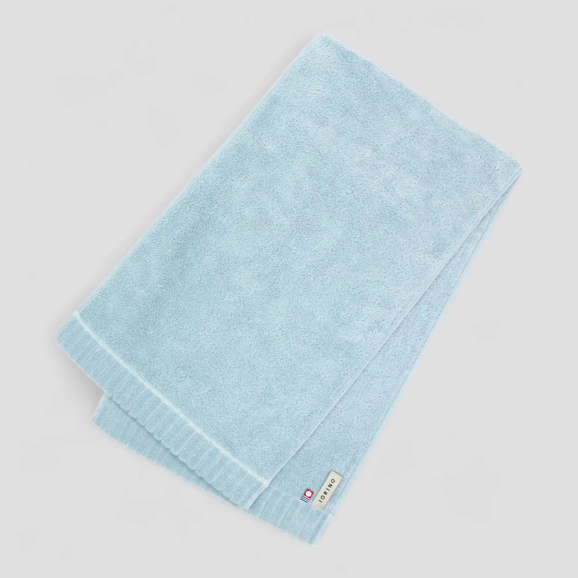 Light blue Imabari towel with a brand label on a light gray background