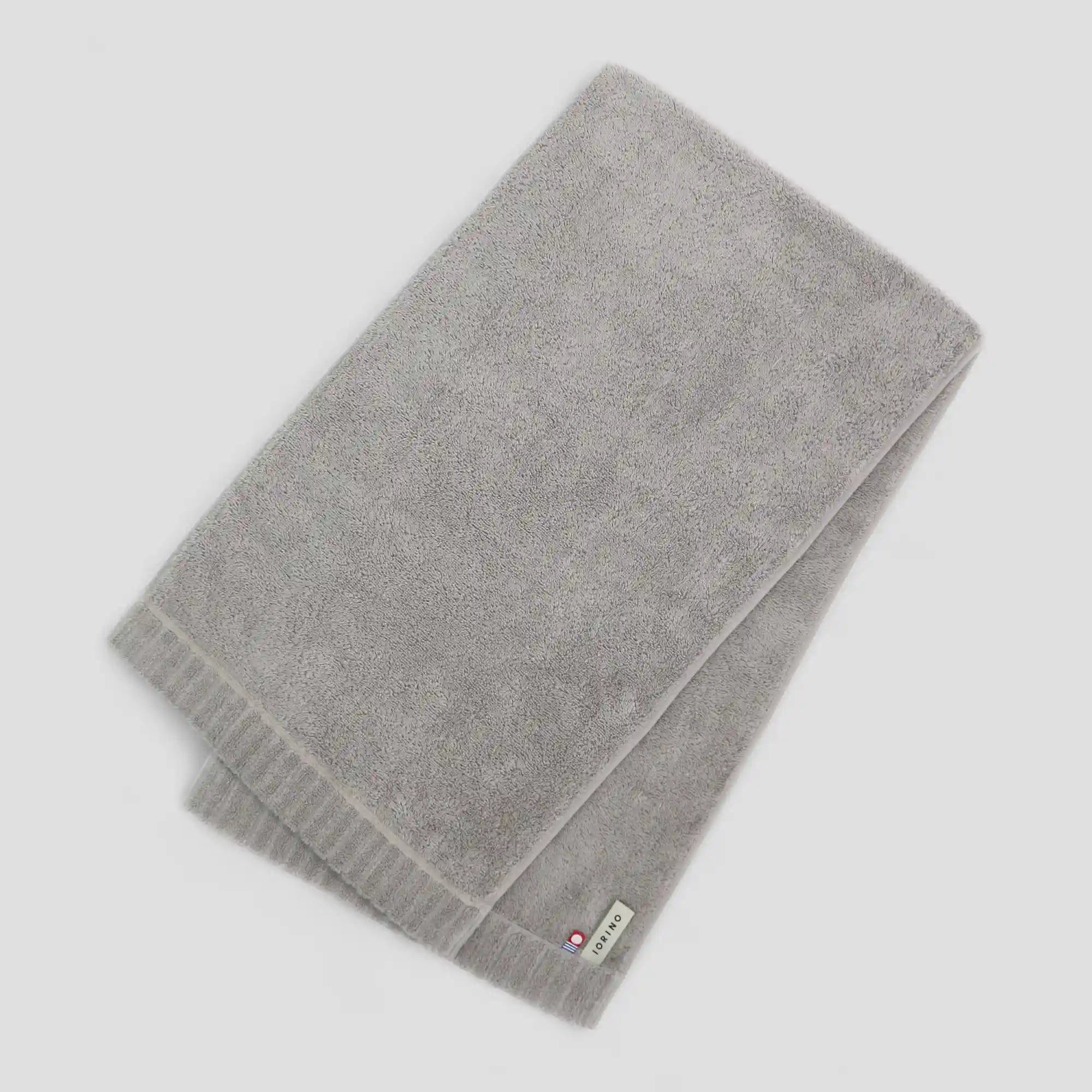 Gray Imabari towel with a brand label on a light gray background