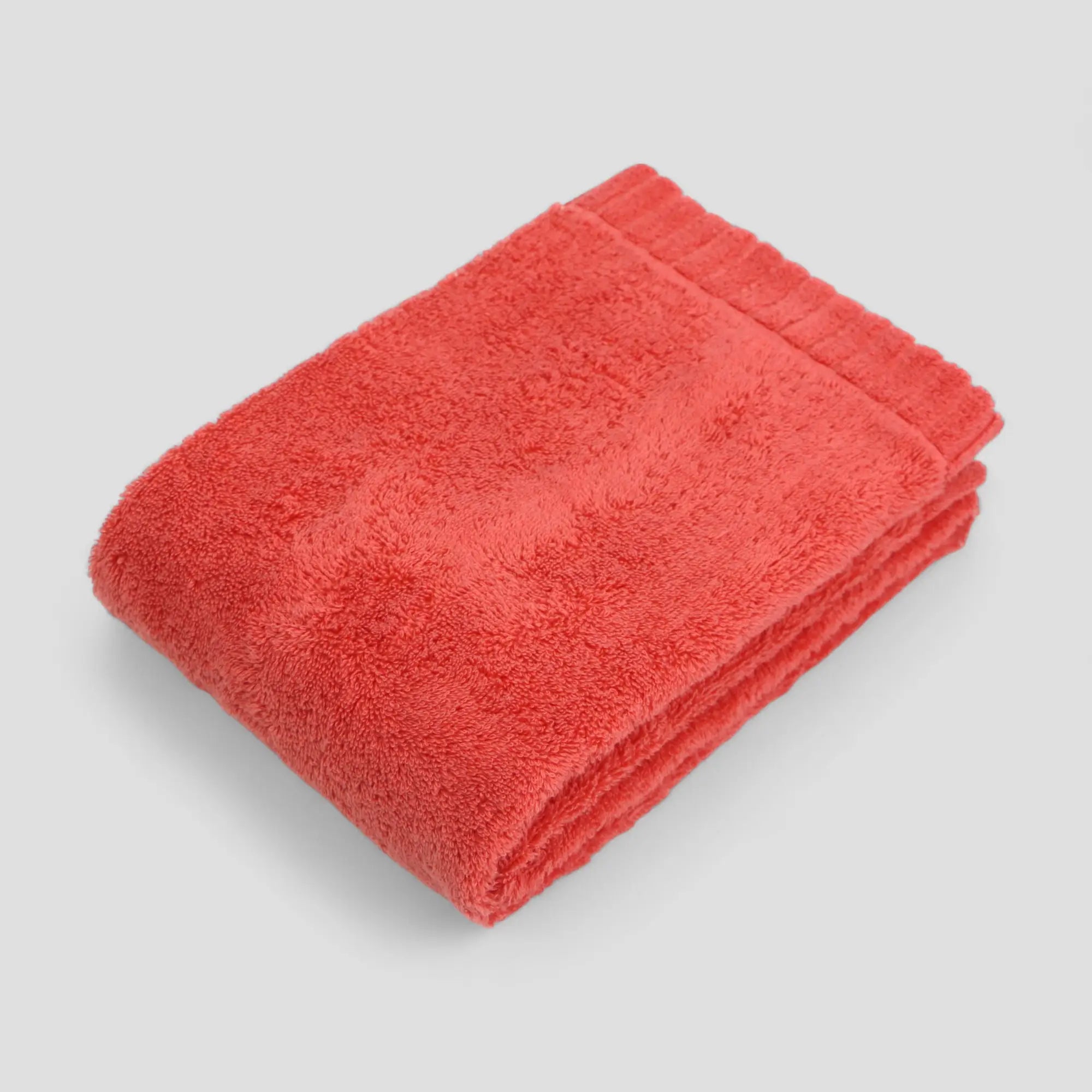 Folded red Imabari towel on a light gray background