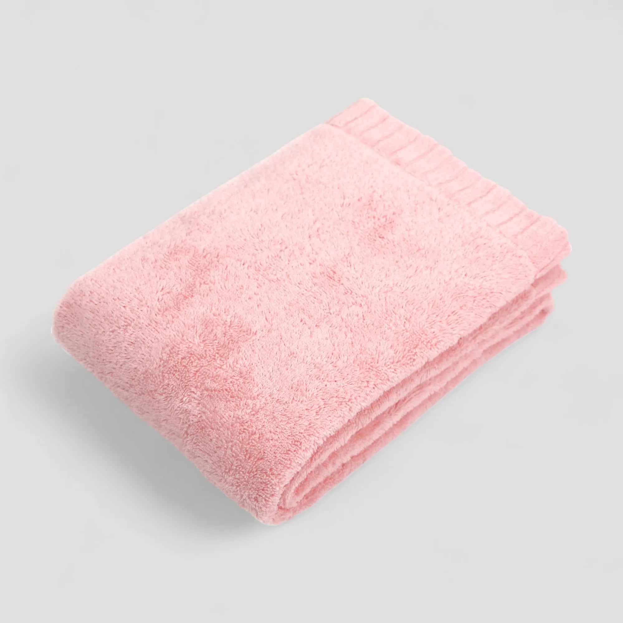 Folded pink Imabari towel on a gray background
