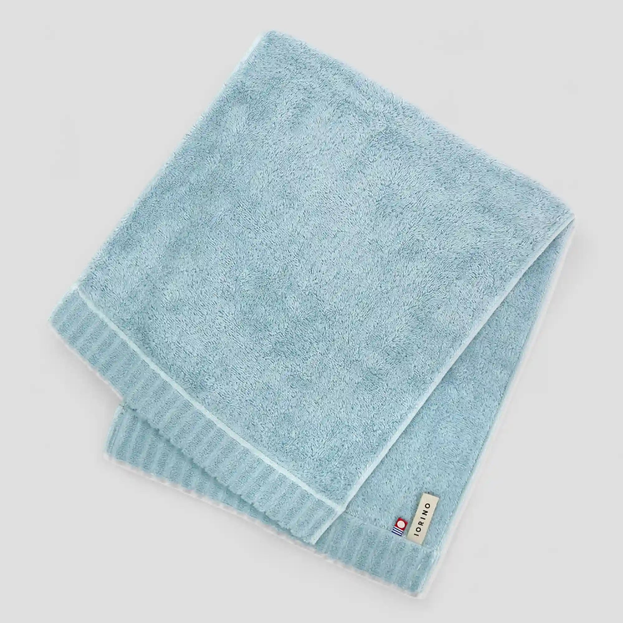 Folded light blue Imabari towel on a white background