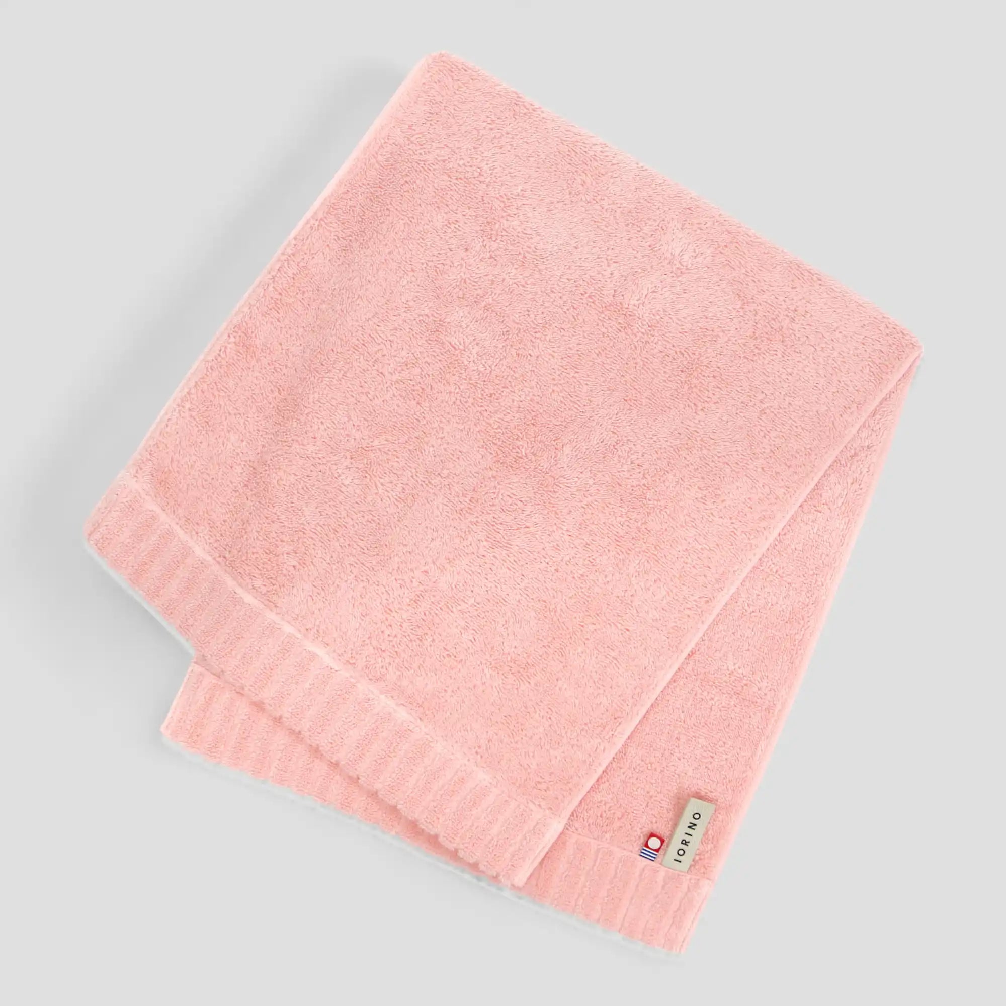 Pink  Imabari towel with a brand label on a gray background