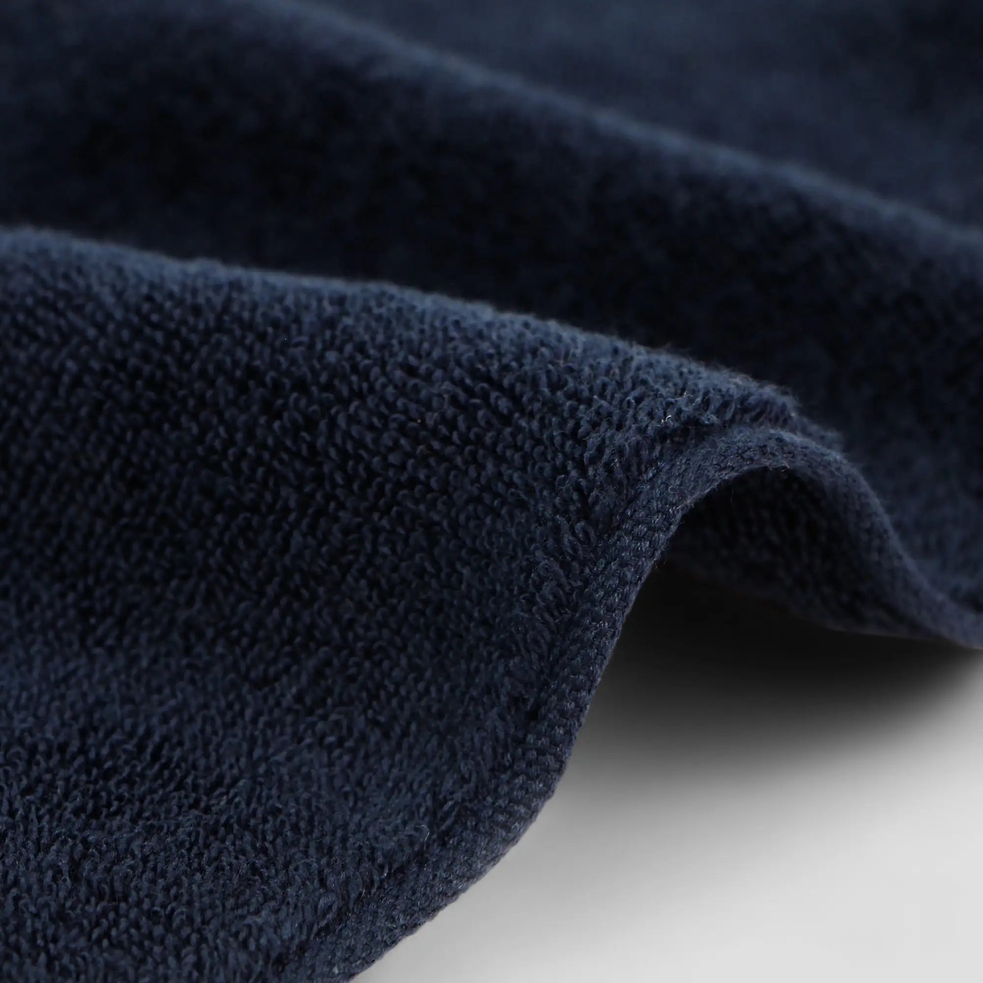 Close-up of a navy blue Imabari towel on a light gray background