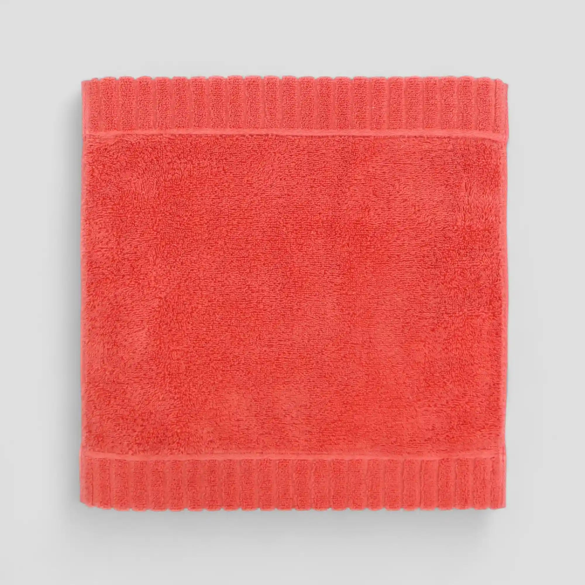 Coral-colored Imabari towel on a light gray background