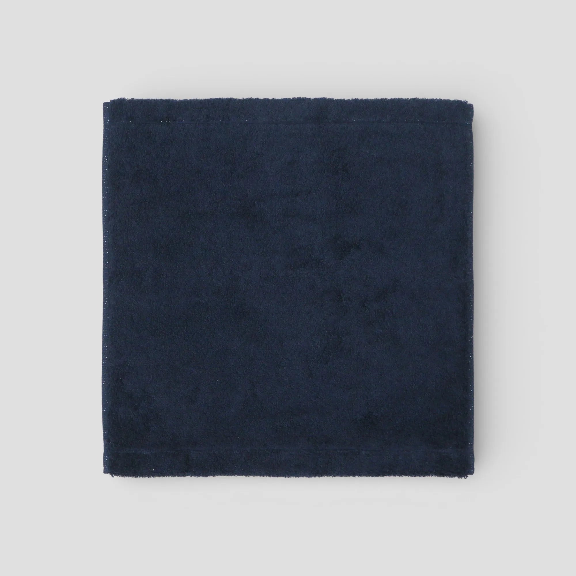 Navy blue fabric square Imabari towel on a light gray background