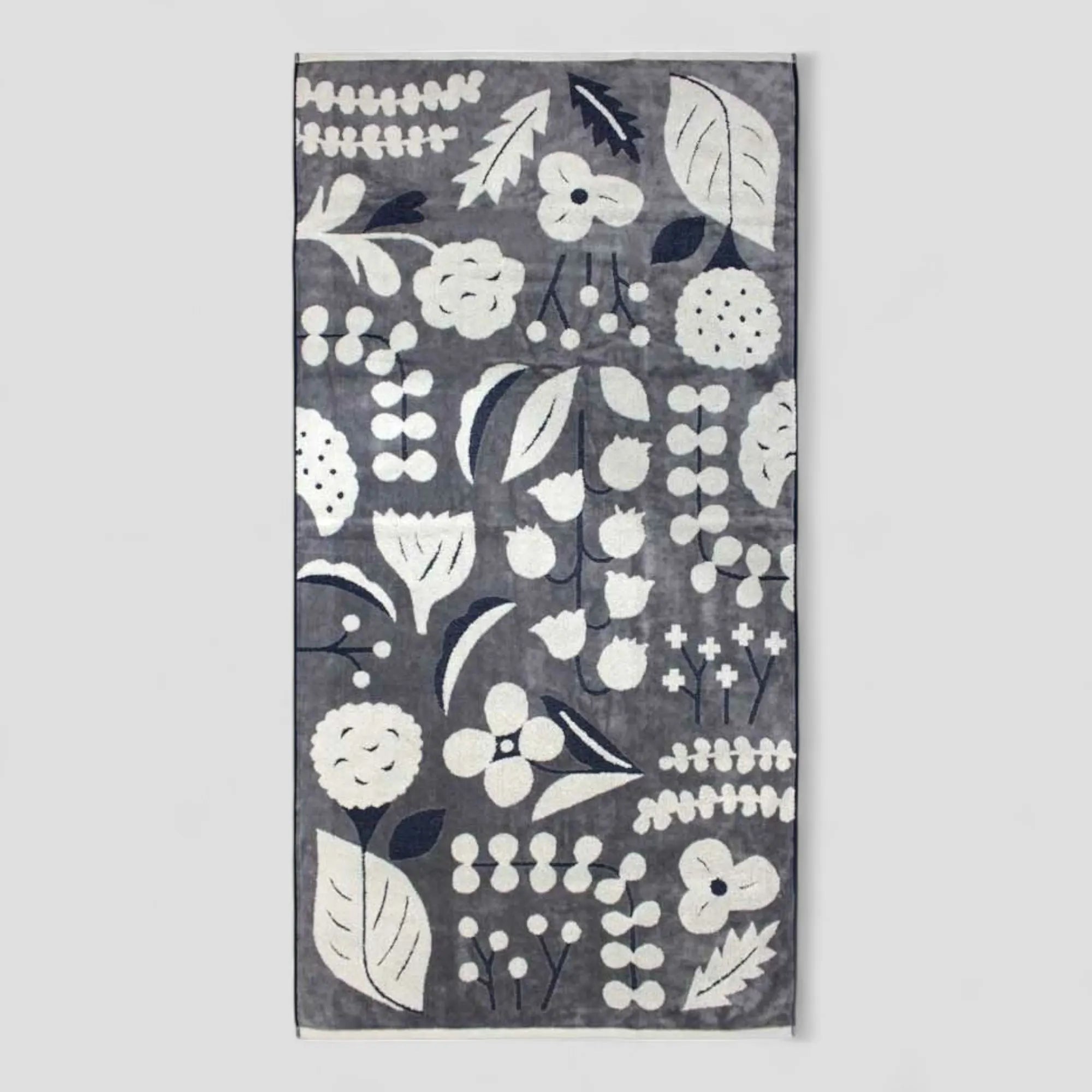 A dark gray floral patterned Imabari towel  with white flowers and leaves 