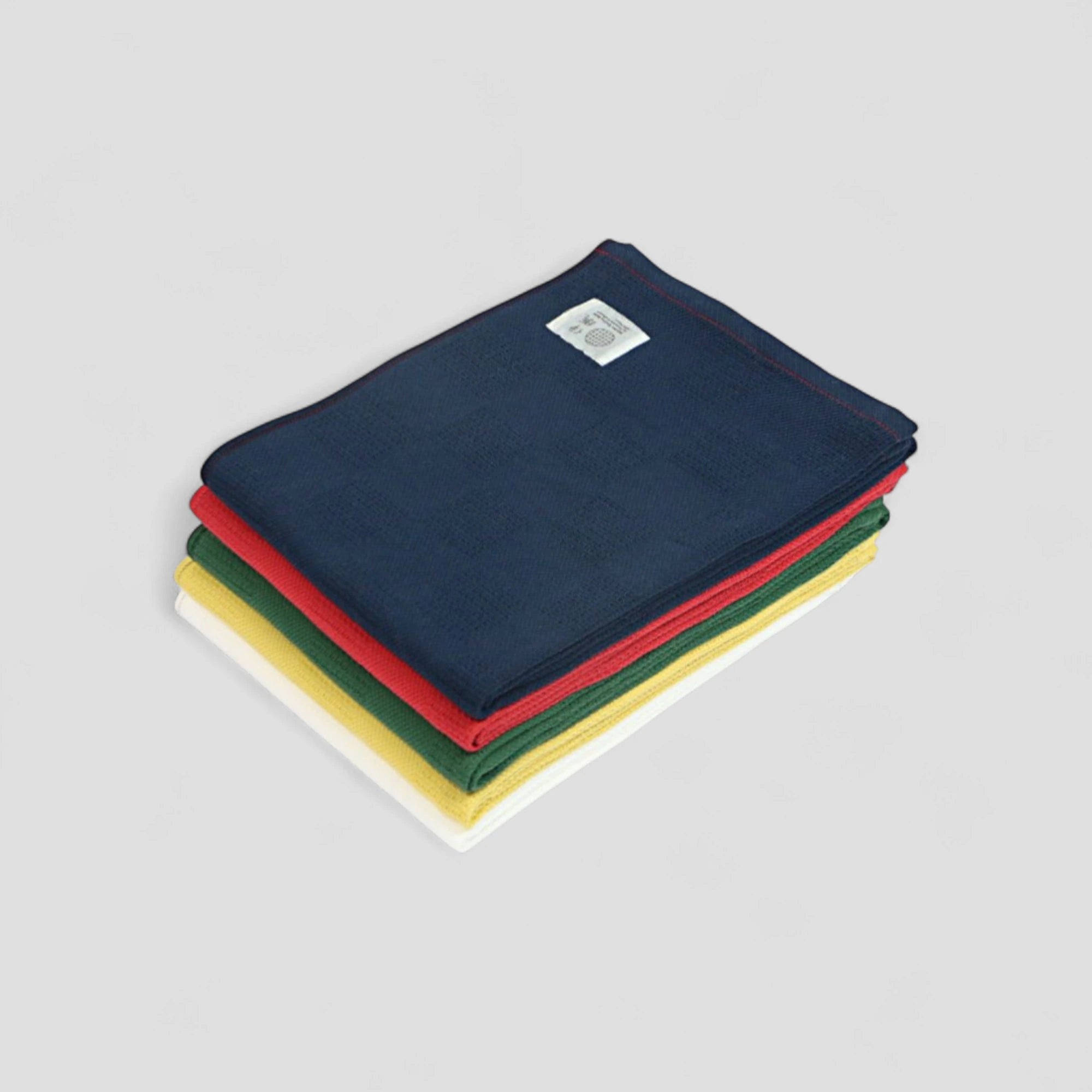 Stack of folded Imabari towel  in navy, red, yellow, white and green on a gray background