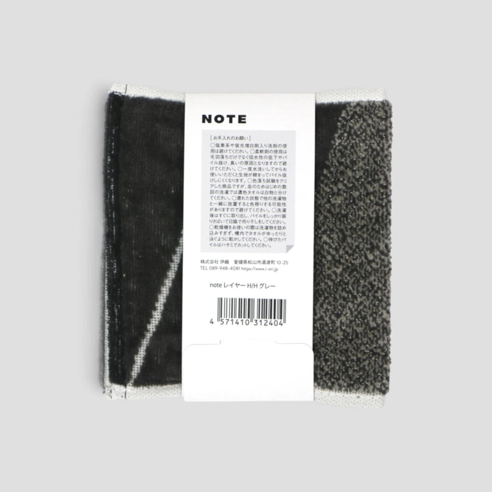 A pair of black and white striped Imabari towel with a white paper label attached, photographed against a solid light gray background.