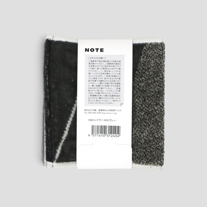 A pair of black and white striped Imabari towel with a white paper label attached, photographed against a solid light gray background.