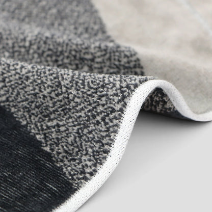 Close-up of a textured Imabari towel with a modern geometric pattern in black, gray, and beige, showing the woven pile and white edge trim.