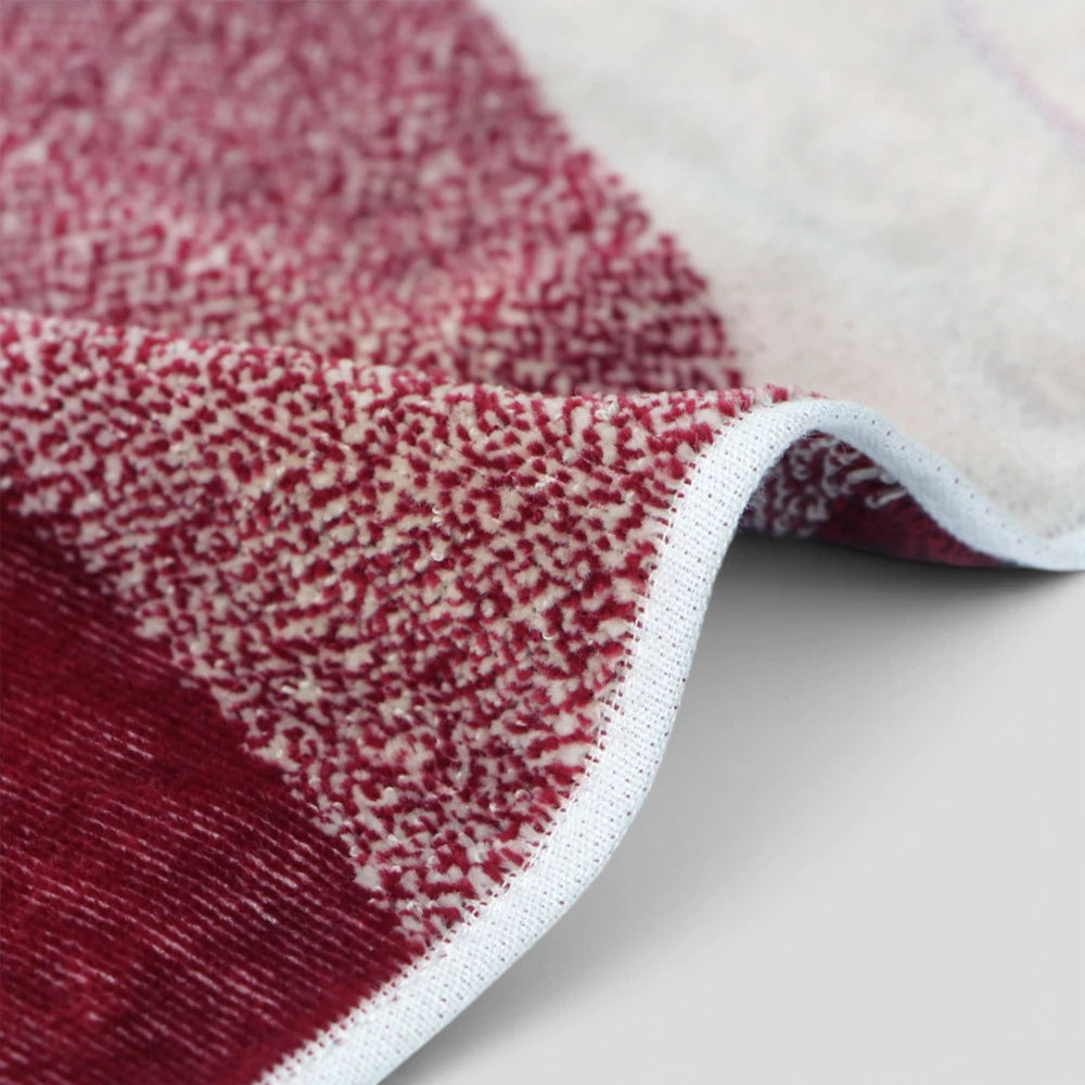 A close-up of a textured Imabari towel with a red and cream speckled pattern and a white stitched border, folded over to show the underside.