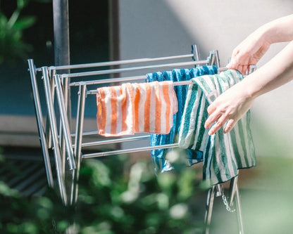 Person hanging striped Imabari towels on a drying rack outdoors